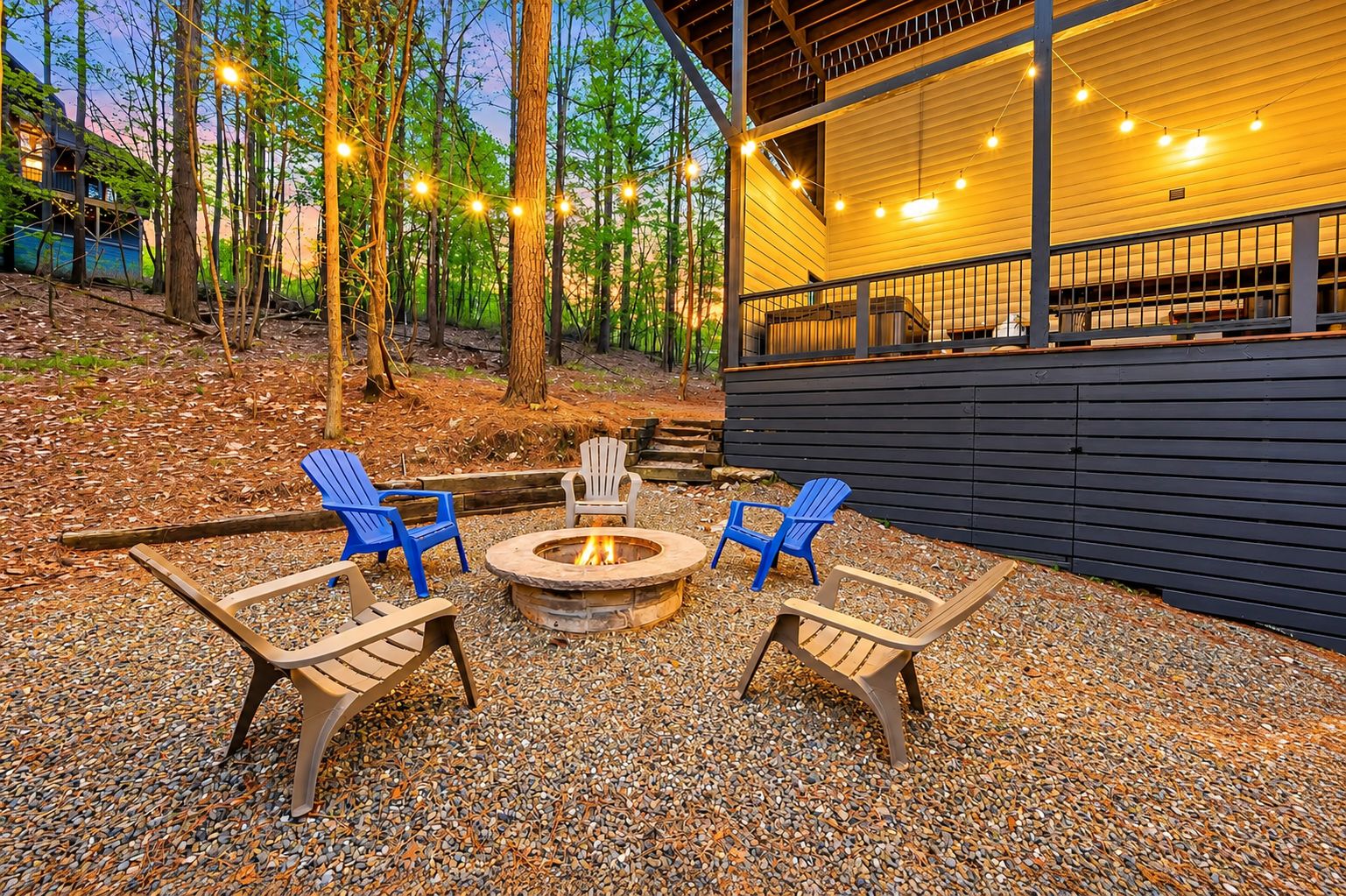 An outdoor seating area with a fire pit and Adirondack chairs.