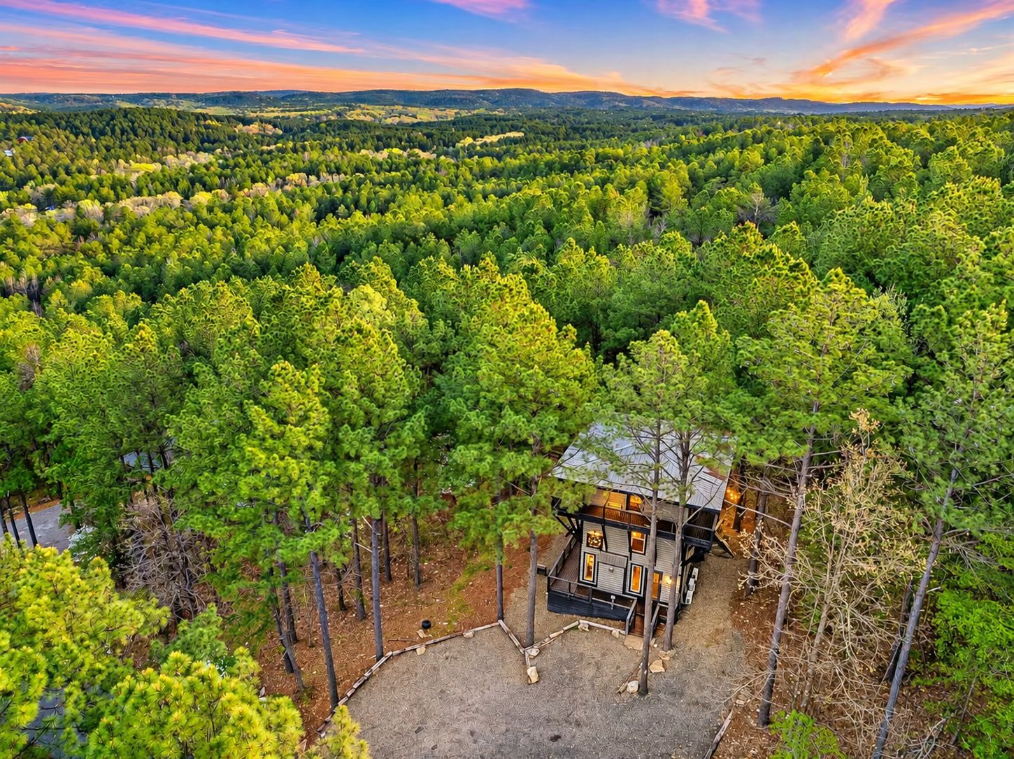 A cabin surrounded by dense forest with a clear view of the landscape.