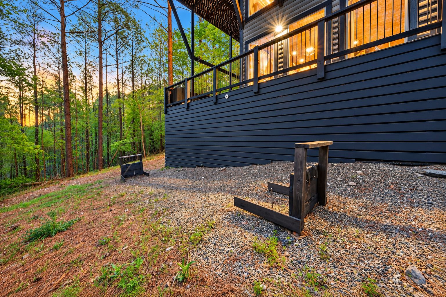 A modern building with a dark exterior, a gravel driveway, and a wooden structure in the foreground.