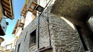 Un carrer estret amb edificis de pedra, balcons i un fanal.