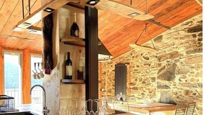 Una cuina rústica amb paret de pedra, sostre de fusta i una prestatgeria de vins de obra.