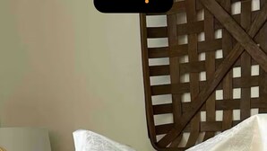 A bed with white and yellow bedding, a wooden headboard, and a decorative pillow with a geometric pattern.