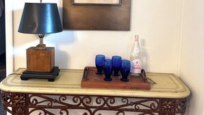 A table with a lamp, a framed sketch, and blue glasses on a tray.