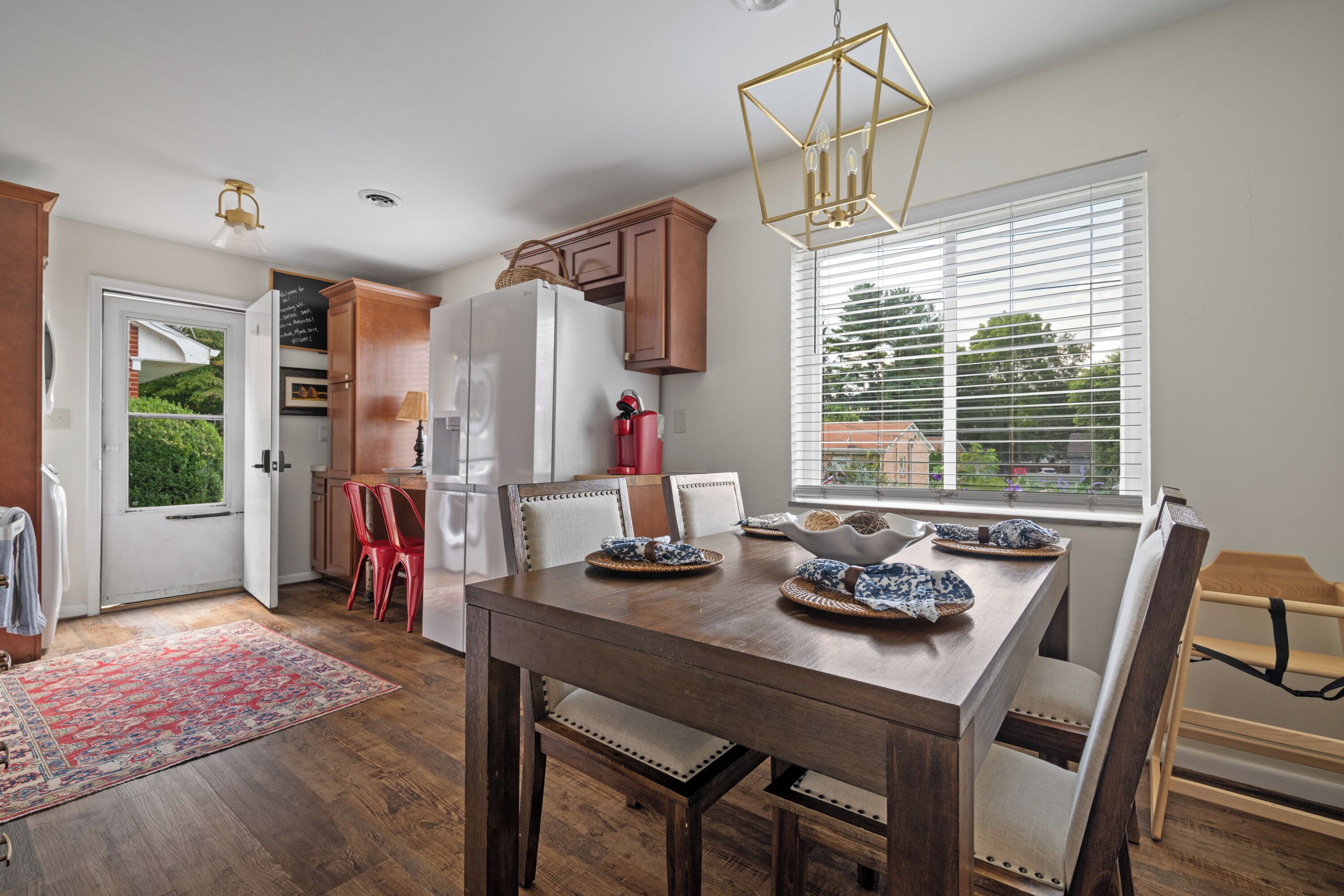 A modern kitchen with a white refrigerator, wooden cabinets, and a dining table set for four.