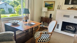 A room with a wooden desk, a polka-dotted chair, a fireplace, and a painting on the wall.