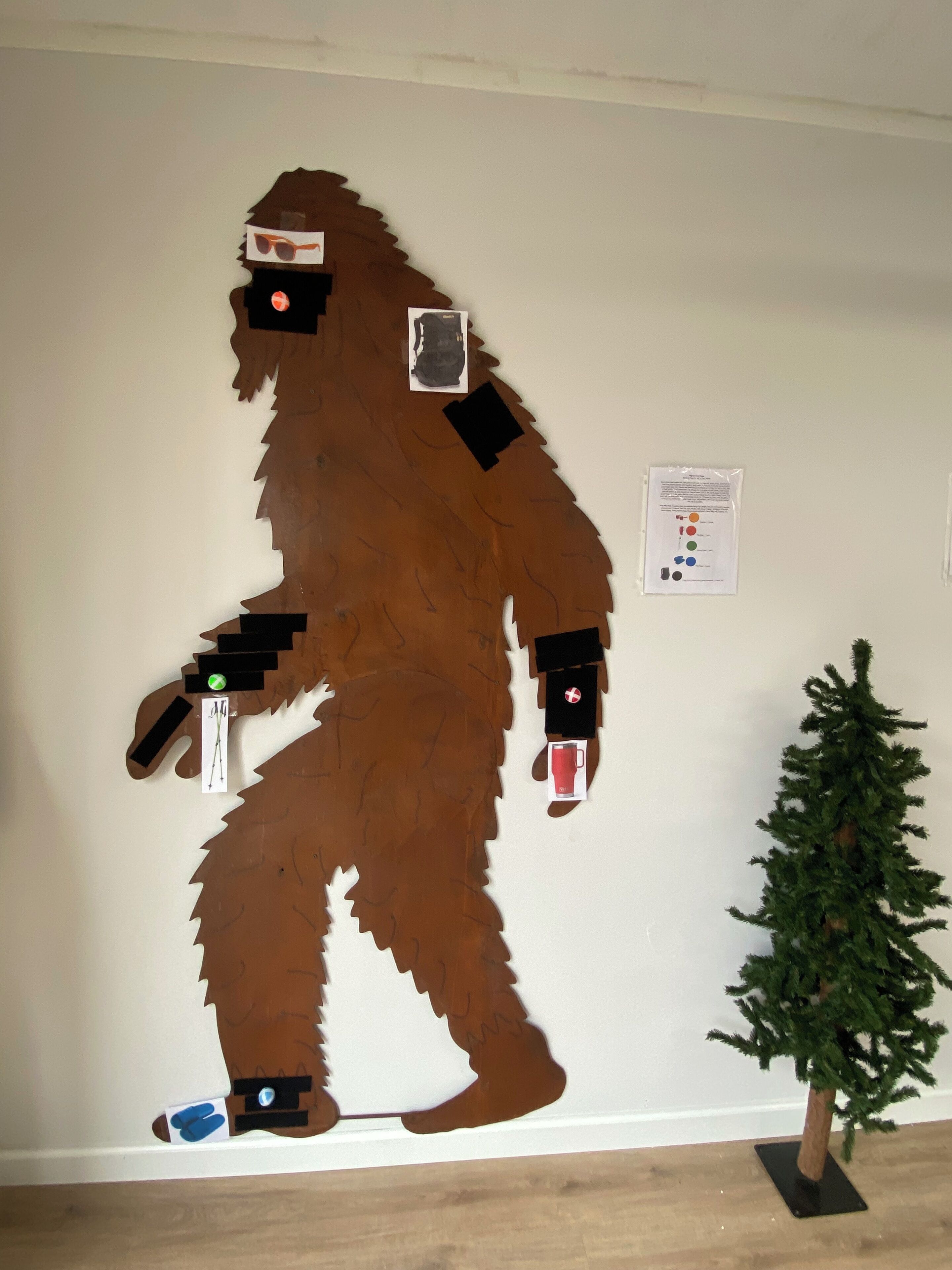 A large bear cutout on a wall, a small Christmas tree, and a sign with color codes.