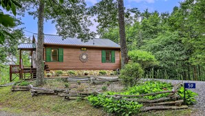 Un rustico chalet con tetto in metallo, persiane verdi e un portico.