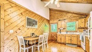 Ambiente in legno con tavolo e sedie, pensili e una finestra.