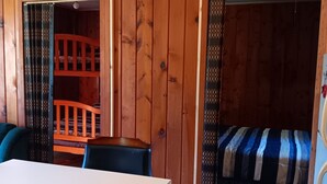 L’intérieur d’une cabane en bois, avec un lit superposé, une table et une chaise.