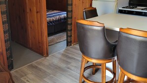 Une pièce aux murs lambrissés, comprenant une table à manger, des chaises, un réfrigérateur et une cuisinière.