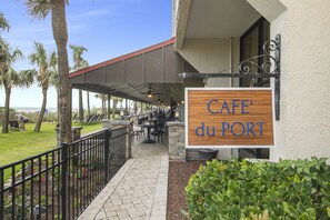 A patio area with outdoor seating, palm trees, and a sign for 'Café du PORT'. - Ocean Reef Resort with POOLS, HOT TUBS, WATER PARK in Myrte Beach, SC 9th floor (Myrtle Beach)
