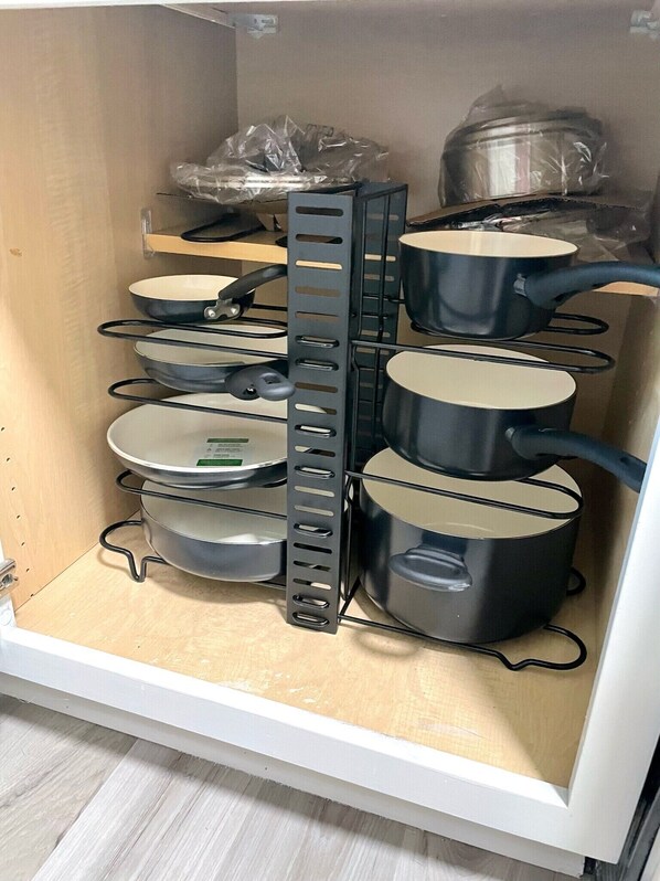Un armario de cocina con varios estantes que contienen ollas y sartenes.