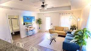 A modern living room with a sofa, coffee table, and a TV displaying a turtle. - Peaceful 3-2 Home w/ Pool, 4min to beach, RV P-king, BBQ, Firepit, Fast Internet (Gulf Breeze)