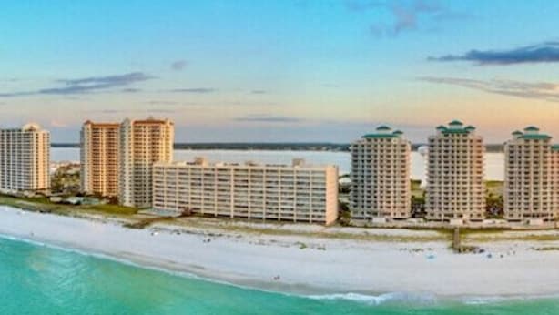 A beachfront hotel with multiple high-rise buildings, a sandy beach, and a clear view of the ocean. - Peaceful 3-2 Home w/ Pool, 4min to beach, RV P-king, BBQ, Firepit, Fast Internet (Gulf Breeze)