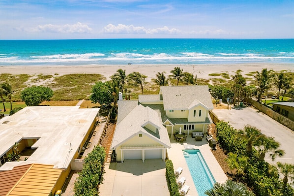 A beachfront property with a swimming pool, a covered patio, and a view of the ocean.