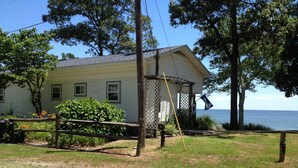 Une maison avec une véranda, une clôture en bois et une vue sur la mer.