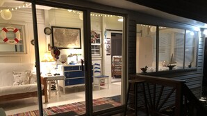 Un intérieur chaleureux avec une terrasse en bois, un canapé, un bureau avec une lampe et une carte accrochée au mur.