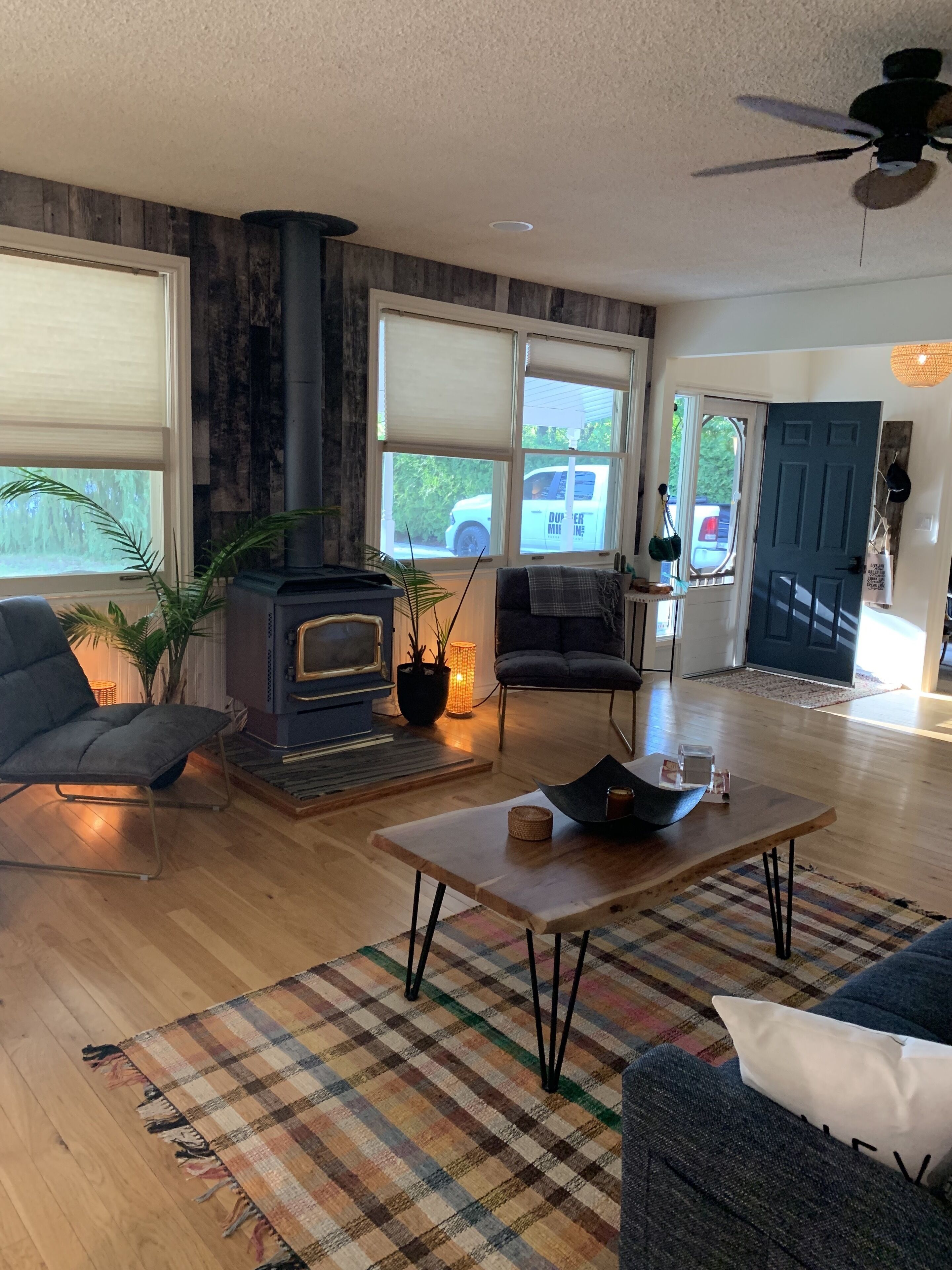 A living room with a wood-burning stove, a sofa, a coffee table, and a view of the outside.
