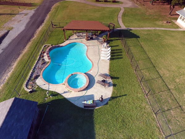 Vue aérienne d’une propriété résidentielle dotée d’une piscine, d’un patio couvert et d’un petit jardin.