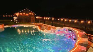 A swimming pool with a stone edge and a wooden deck.