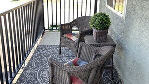 Ein Balkon mit Korbmöbeln, einem Blumentopf und Blick auf Nachbarhäuser.