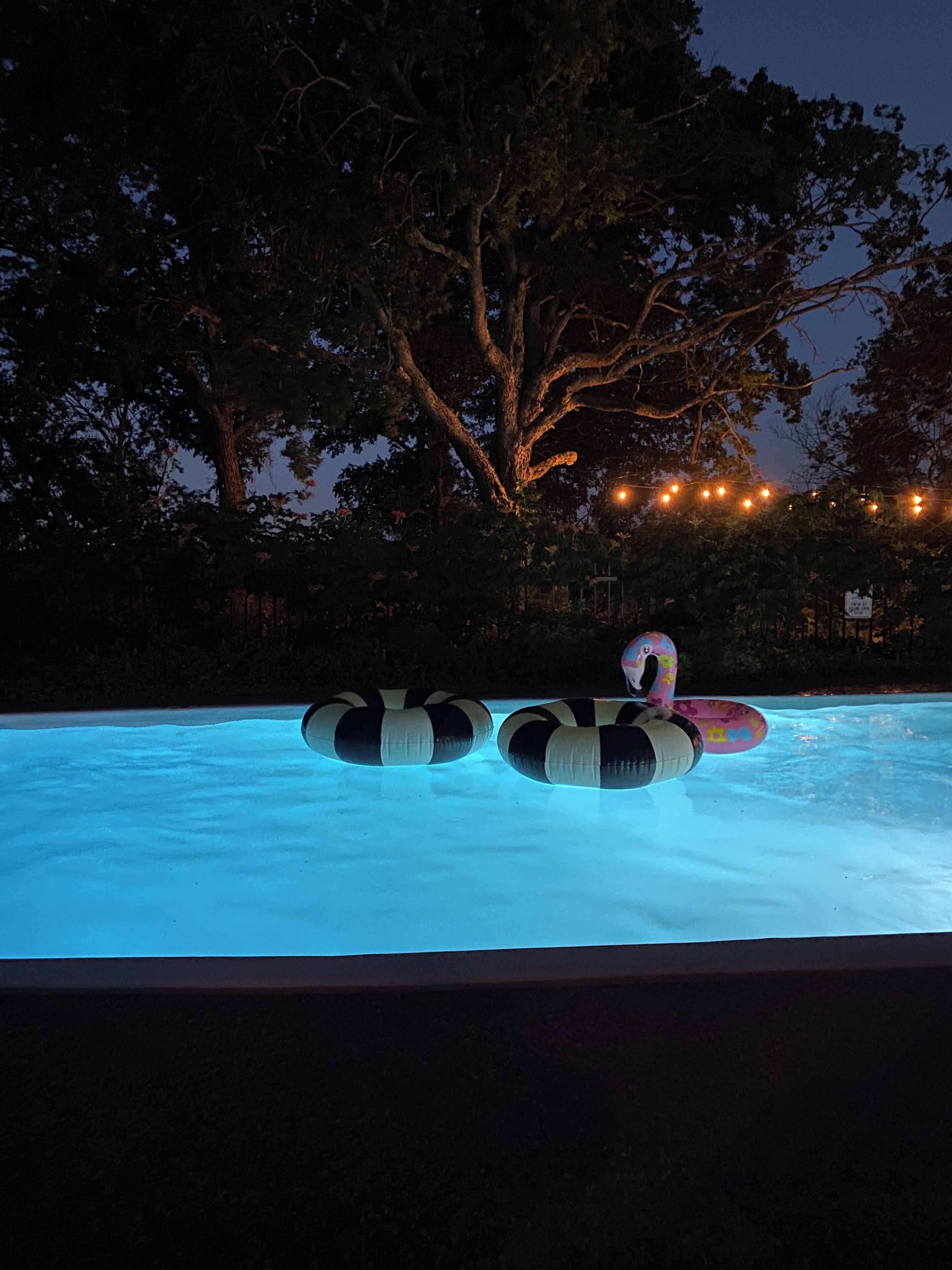 A swimming pool with inflatable rings and a person in a swimsuit.
