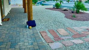 A building with a covered outdoor area, a gravel pathway, and a view of a distant landscape with mountains and palm trees. - Luxury Lake View Villa with  Pool, Spa, Sleeps 14, Boat parking (Lake Havasu City)