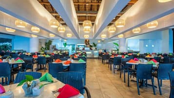 Un restaurante espacioso con techos altos, iluminación colgante moderna y una zona de bar central.