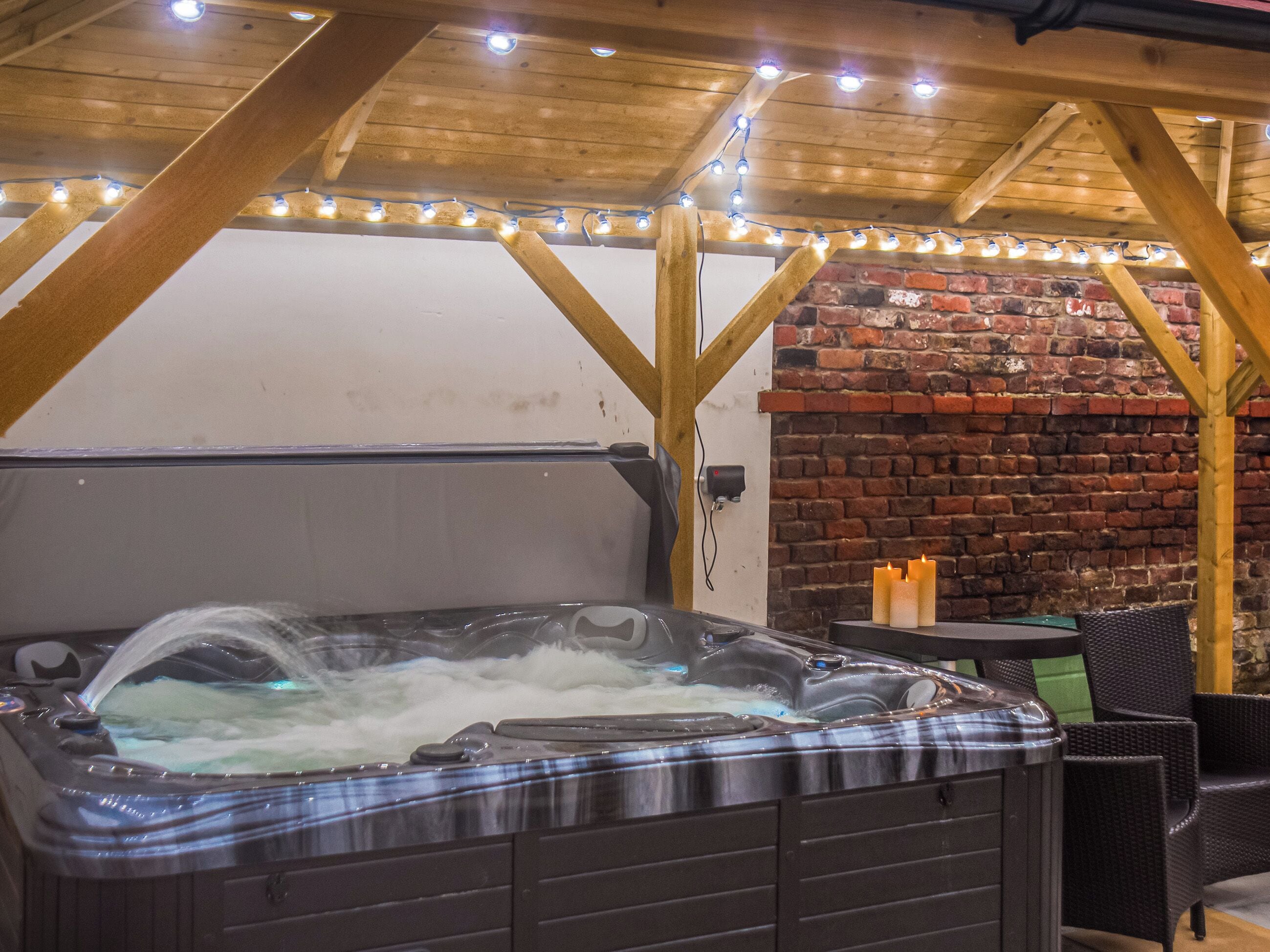 A hot tub with a wooden ceiling and brick wall in the background.