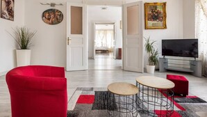 Ein modernes Wohnzimmer mit einem roten Sofa, einem Fernseher und einem Essbereich mit einem kleinen Tisch und Stühlen.