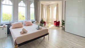 Ein geräumiges Schlafzimmer mit einem großen Bett, einem Kleiderschrank, einem Schreibtisch und einem roten Sessel.