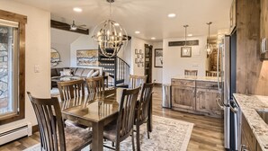 A modern kitchen with a central island, wooden chairs, and a chandelier. - Ski-In Ski-Out, Skiwatch - Peak 8 Breckenridge, Sleeps 12  Newly Renovated (Breckenridge)