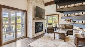 A spacious living room with a stone fireplace, large windows, and a modern staircase. - Ski-In Ski-Out, Skiwatch - Peak 8 Breckenridge, Sleeps 12  Newly Renovated (Breckenridge)