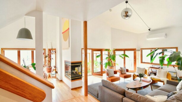 A spacious living area with a wooden staircase, large windows, and a fireplace. - Spacious Designer Home in Boulder Perfect for Families and Groups (Boulder)