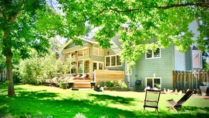 A house with a large deck, a covered patio, and a well-maintained lawn. - Spacious Designer Home in Boulder Perfect for Families and Groups (Boulder)