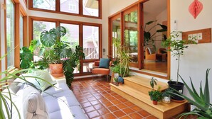 A sunlit room with large windows, a sofa, and various potted plants. - Spacious Designer Home in Boulder Perfect for Families and Groups (Boulder)