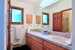 A bathroom with two sinks, wooden cabinets, a large mirror, and a window. - Spacious Architect Home Ideal for Families +Groups (Boulder)