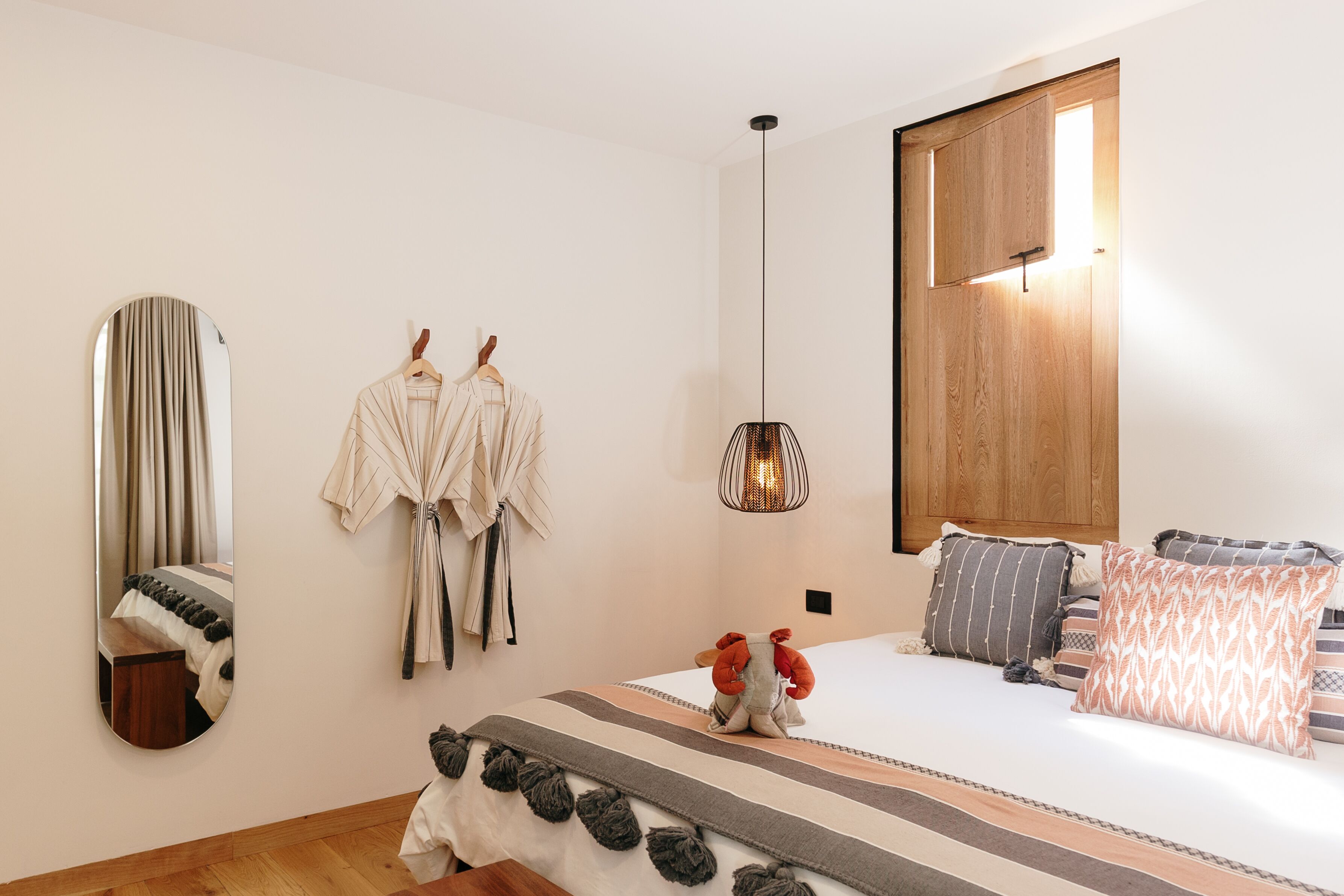 Une chambre à coucher avec un lit, une robe suspendue, un miroir et une lampe suspendue.