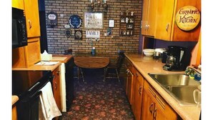 Een keuken met houten kastjes, een bakstenen muur, een koffiezetapparaat en een bordje met de tekst 'Grandma's Kitchen'.