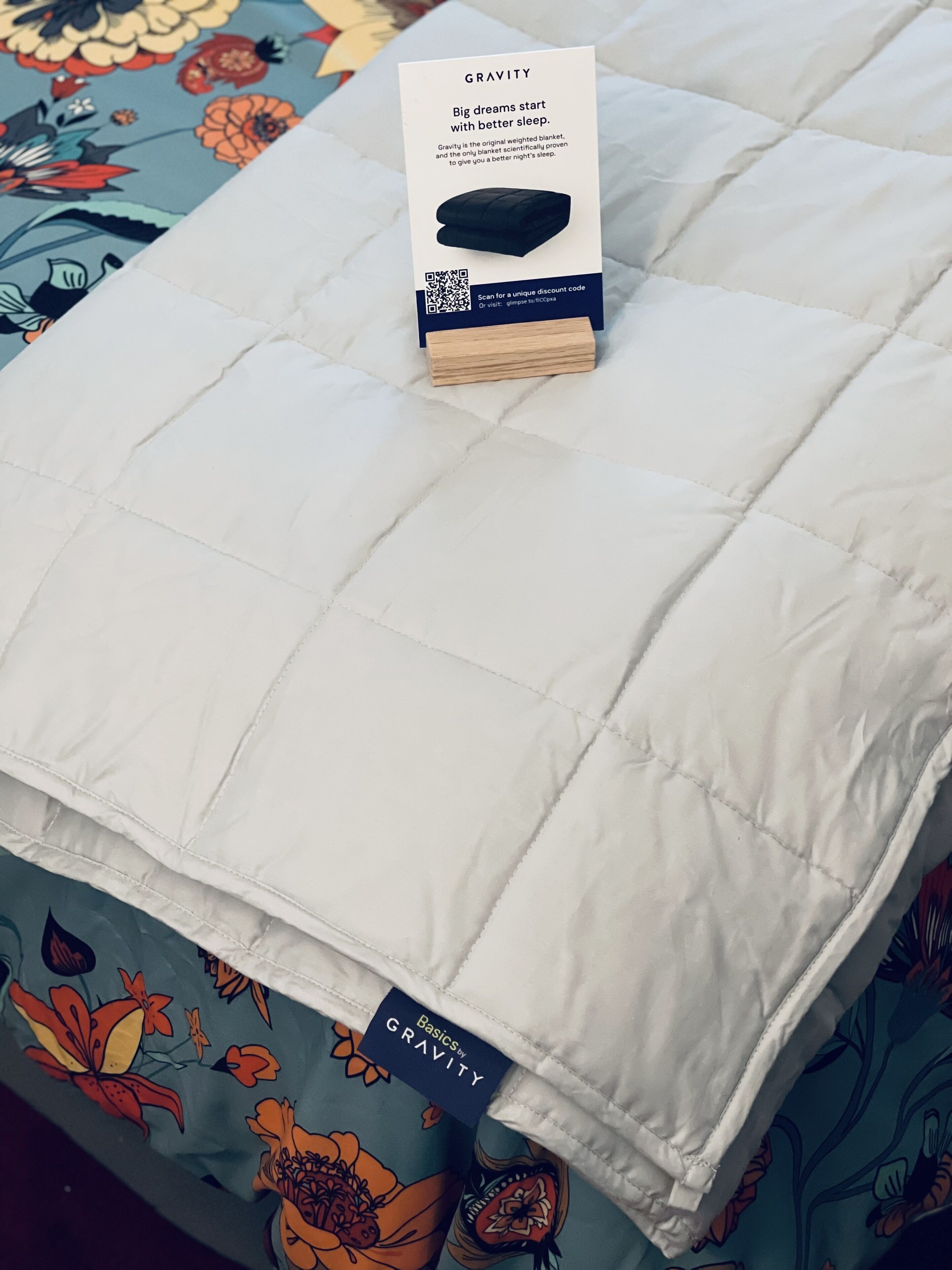 A white quilted mattress with a Gravity brand tag and a promotional flyer on top.