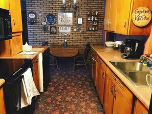 Een keuken met houten kastjes, een bakstenen muur, een koffiezetapparaat en een bordje met de tekst 'Grandma's Kitchen'.