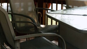 A covered outdoor seating area with metal chairs and a table, overlooking a body of water. - River & Bay Views! Shirley’s Temple! BAY CITY, MI (Bay City)