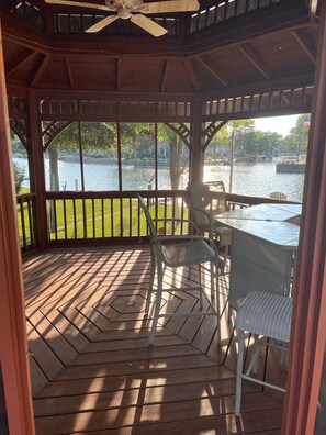Une terrasse couverte avec vue sur un lac, une table et des chaises.