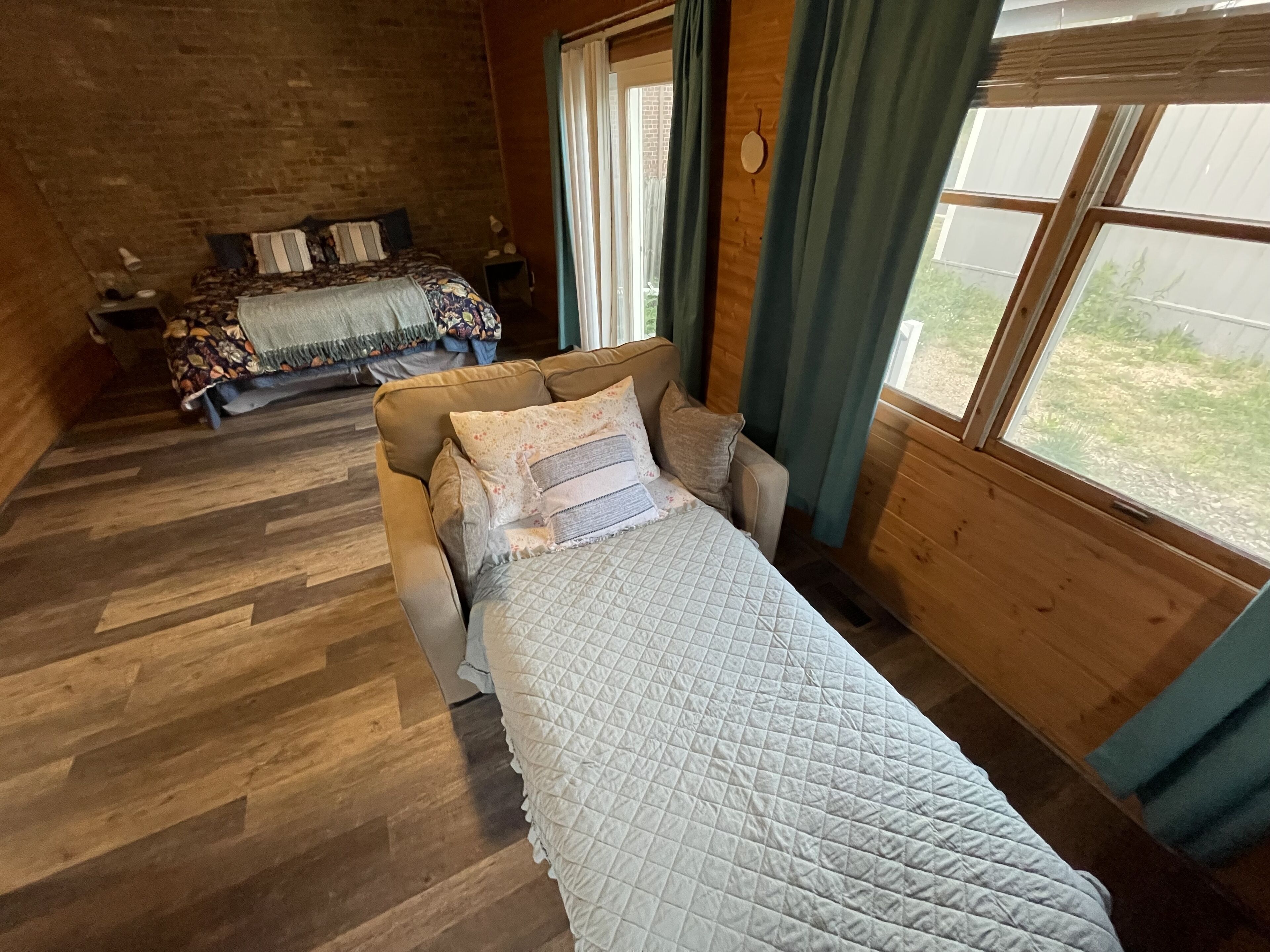 Une pièce confortable avec un lit, un canapé et une fenêtre.