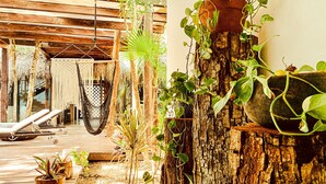 Eine Holzterrasse mit Liegestühlen, Hängematten und Blumentöpfen.
