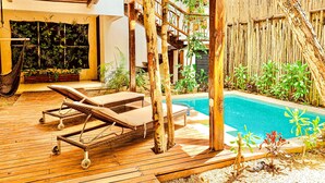 Eine Holzterrasse mit Liegestühlen, einem Pool und einem Bambuszaun.