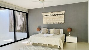 Ein Schlafzimmer mit einem Bett, einem Deckenventilator, einem großen Fenster mit Vorhängen und einem Wanddekor.