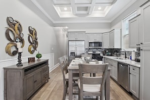 Una cocina moderna con electrodomésticos de acero inoxidable, un comedor con mesa y sillas de madera, y decoración en las paredes.