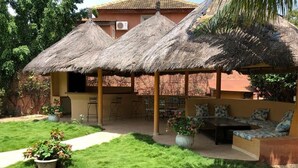 A patio area with a thatched roof, outdoor seating, and a small bar area. - Villa within walking distance to the beach!!! (Saly)