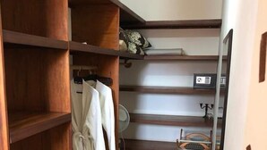 A walk-in closet with wooden shelving, a hanging rack, and a small table with a fan. - Villa within walking distance to the beach!!! (Saly)